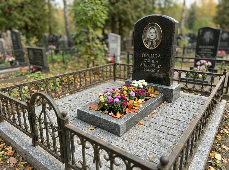 Благоустроенное захоронение с гранитной плиткой, оградой и цветником в Оренбурге