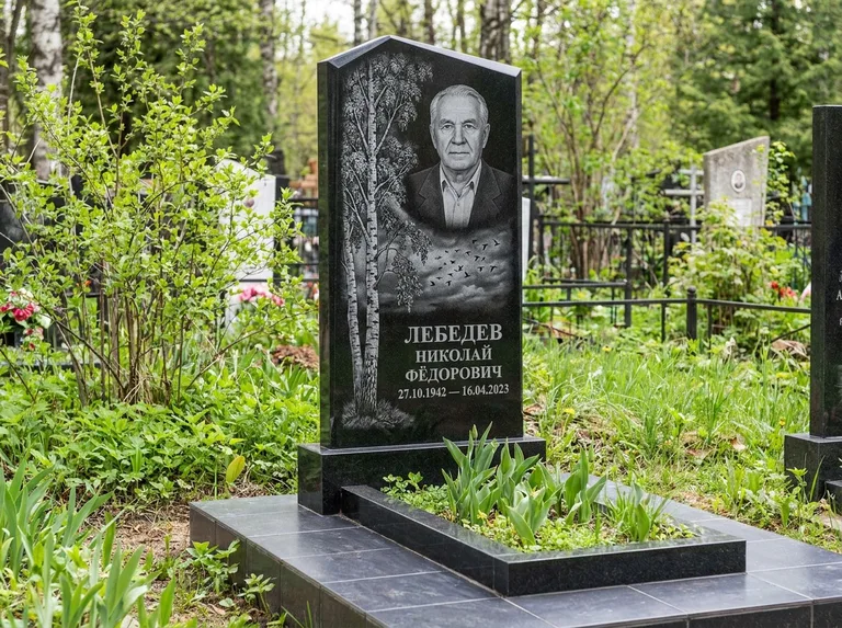 Памятник с гравировкой берёзы: вертикальная стела со скошенным верхом — берёза и стая птиц в небе, гранитный цоколь с тёмной плиткой, работа «Лебедев» в Оренбурге