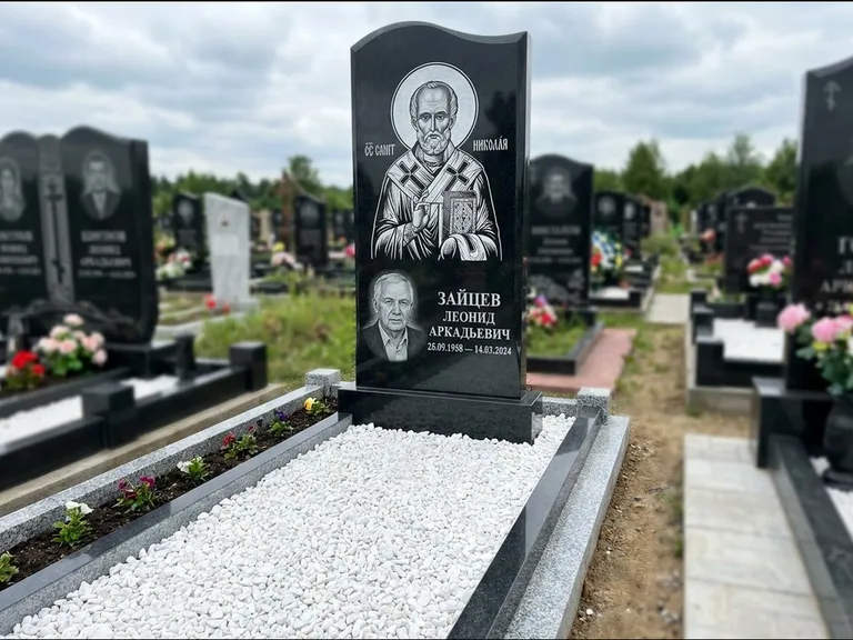 Памятник с гравировкой иконы: стела с крестообразным навершием — икона в резной рамке-киоте, газон без ограды, стриженая трава, работа «Раевская» в Оренбурге