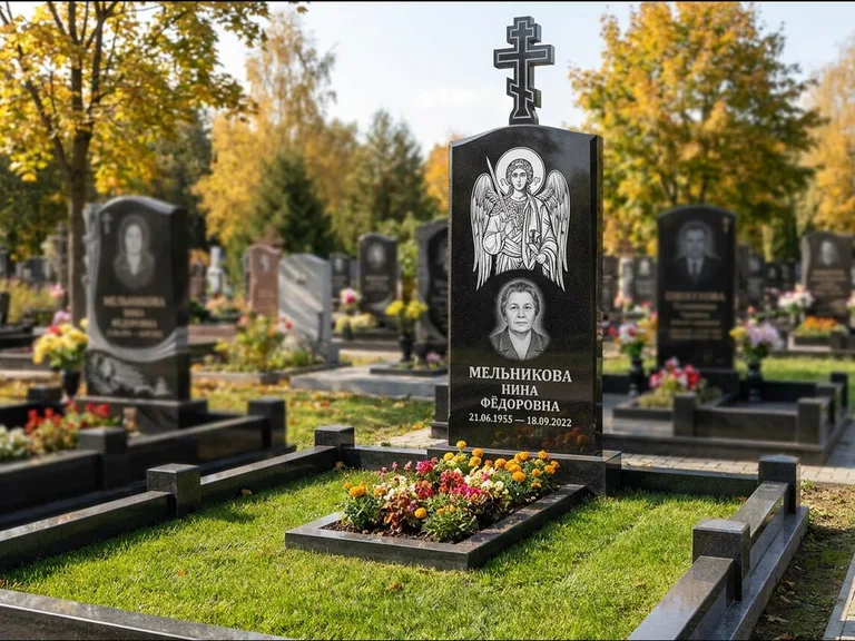 Памятник с гравировкой иконы: округлая стела-медальон с ликом — гравировка Богородицы «Семистрельная», луговые травы и полевые цветы за участком, работа «Гущин» в Оренбурге