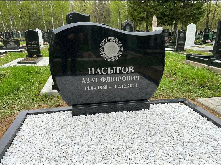 Мусульманский памятник: стела с волнообразным скошенным верхом — гравировка мечети под полумесяцем и звёздами, белая мраморная крошка с бордюром, работа «Насыров» в Оренбурге