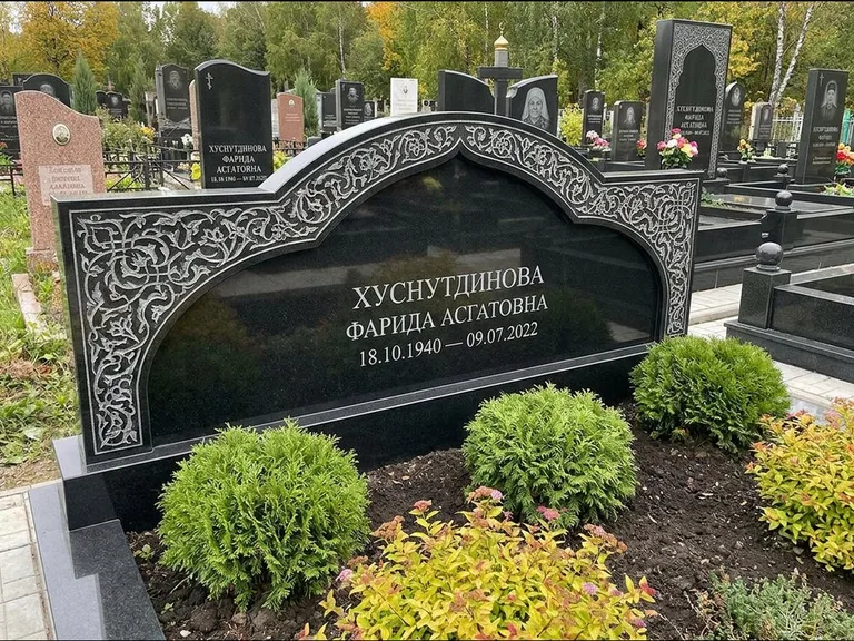 Мусульманский памятник: вытянутая горизонтальная семейная стела с аркой — белая гравировка силуэта мечети с минаретами, участок с декоративными кустами, работа «Зарипова» в Оренбурге
