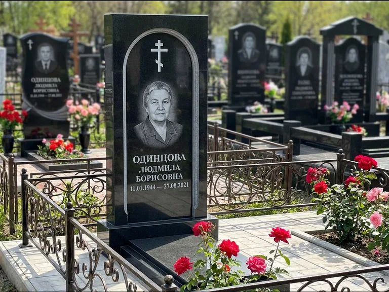 Памятник из чёрного гранита — скромная невысокая стела с крестом с терновым венцом, работа «Лаврентьева» в Оренбурге