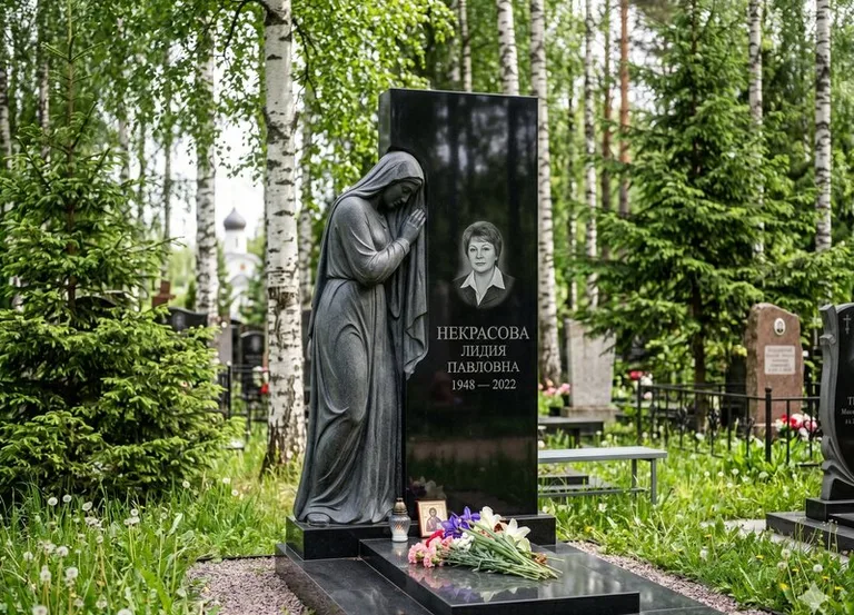 Гранитная фигура скорбящего мужчины у чёрной стелы в Оренбурге